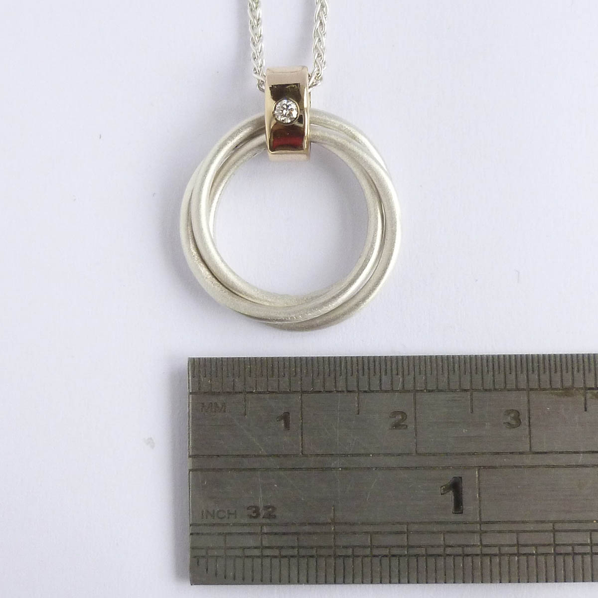 Detail of contemporary Russian ring pendant with interlocking silver rings and gold loop