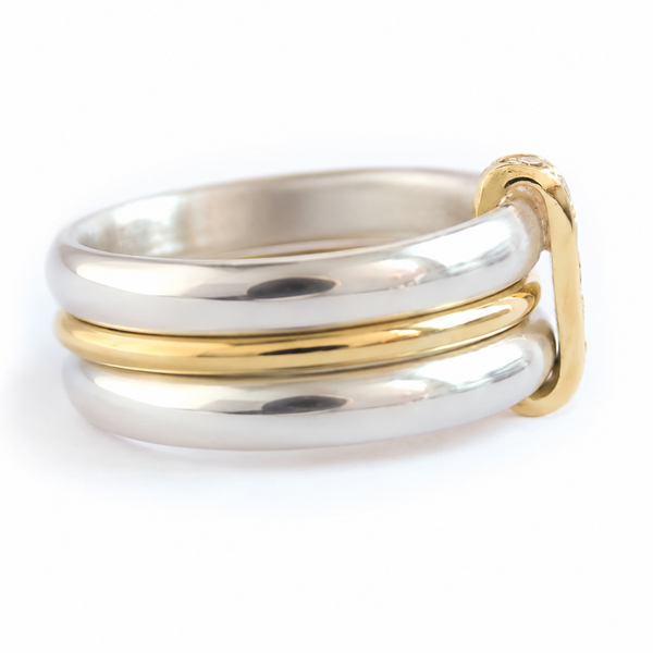 A handmade three band ring featuring two silver bands and one gold band, with a looping joining the bands with a polished finish.