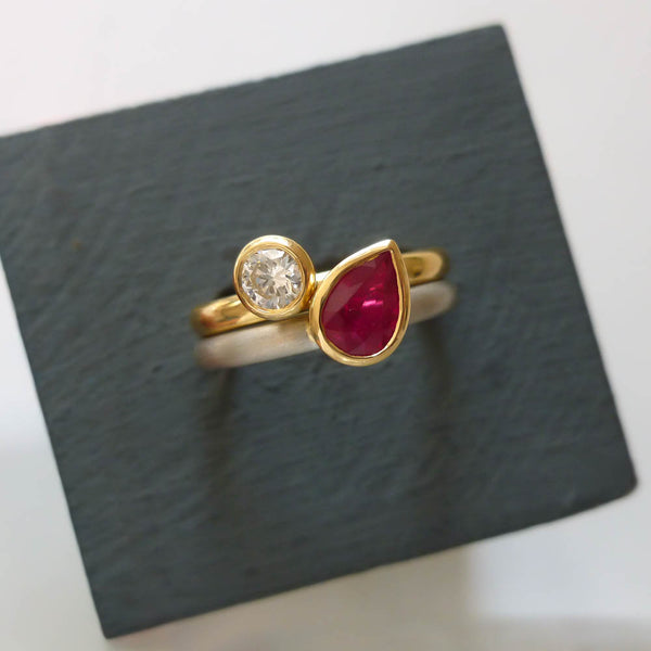 Close-up of the vibrant ruby and diamond detail in a bespoke two-tone gold and platinum ring set.