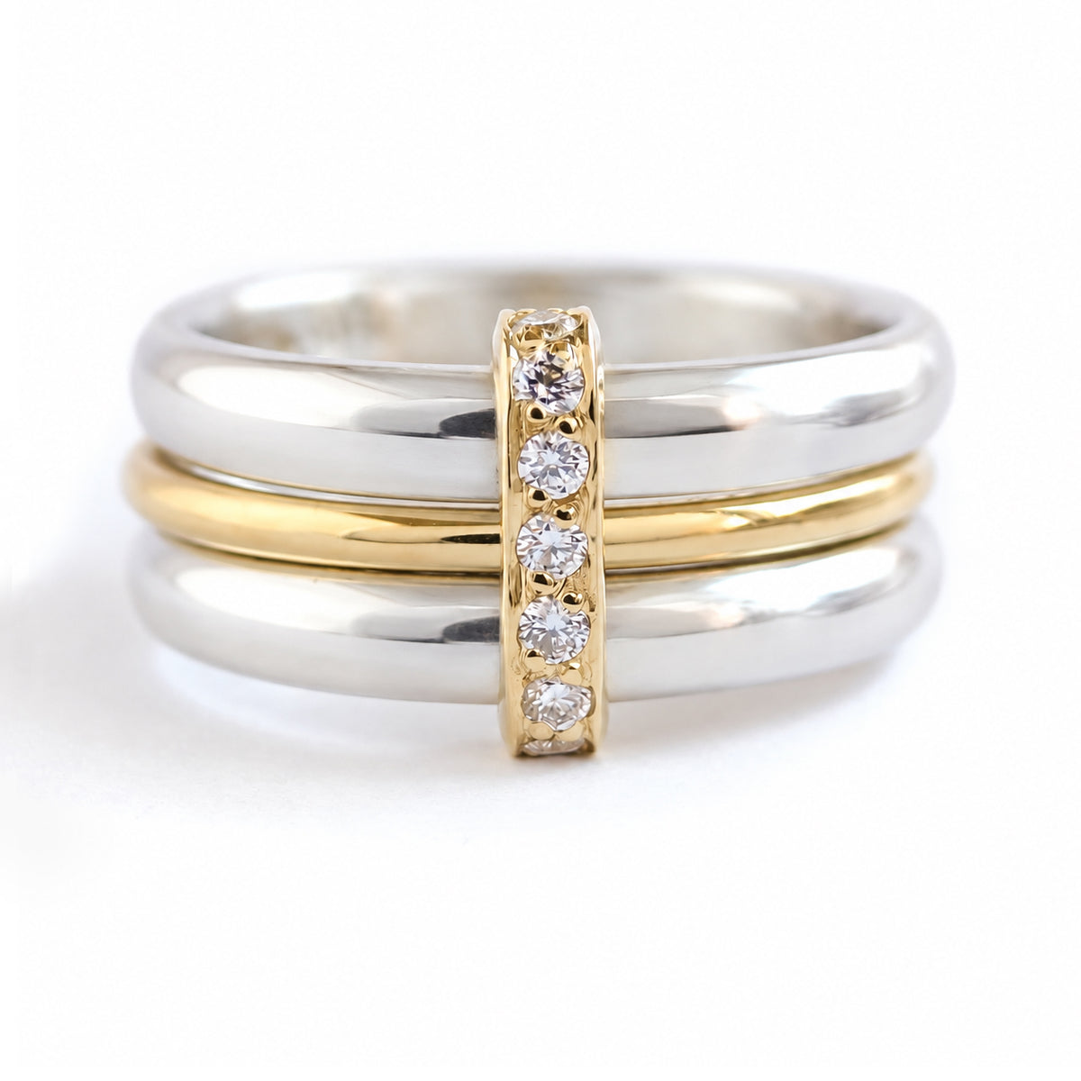 A three band stack ring set featuring two silver bands with  a yellow gold band nestled in the middle, and a central vertical gold bar set with natural ethically sourced white diamonds.