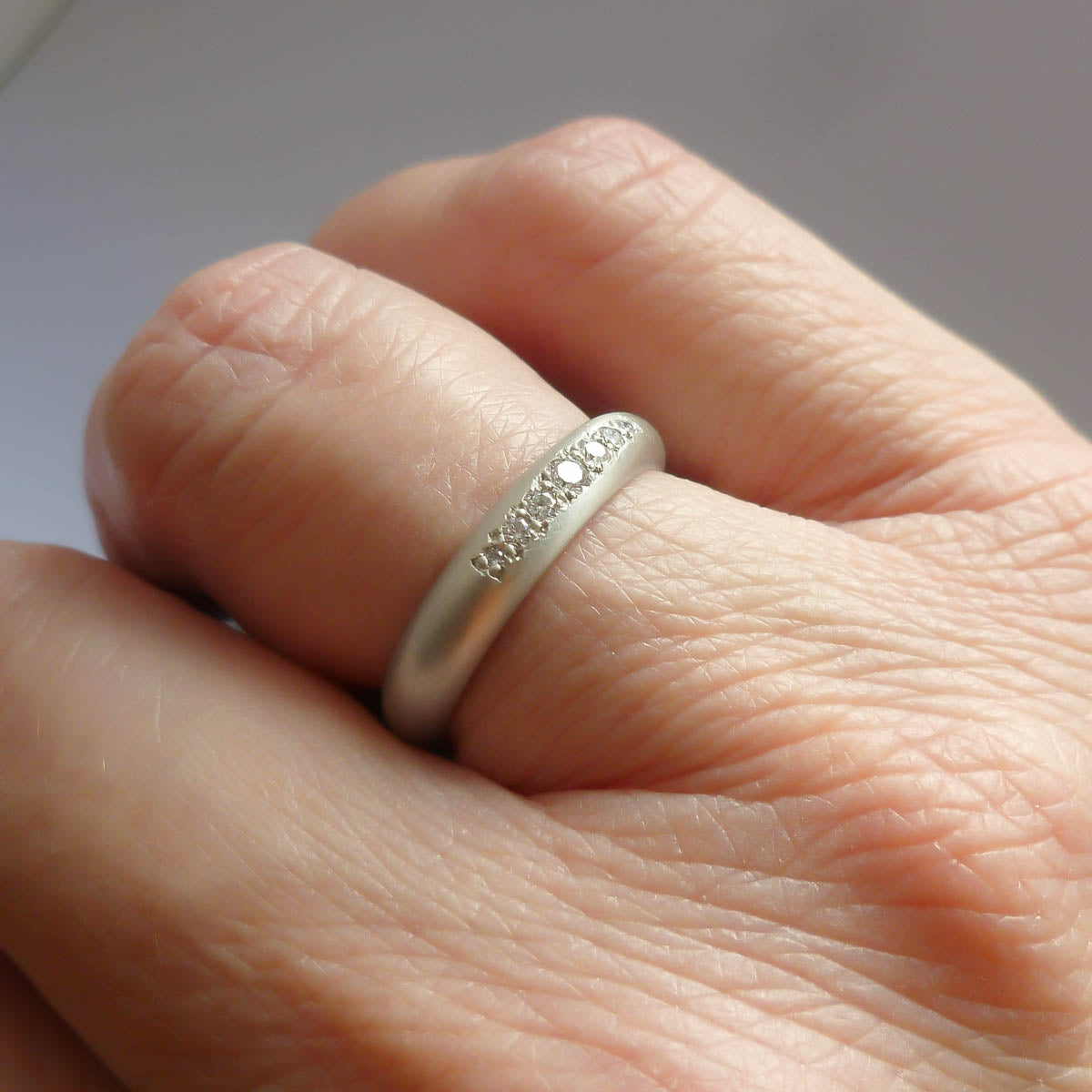 A contemporary white gold diamond ring worn as a unique and modern wedding band.