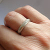 A contemporary white gold diamond ring worn as a unique and modern wedding band.