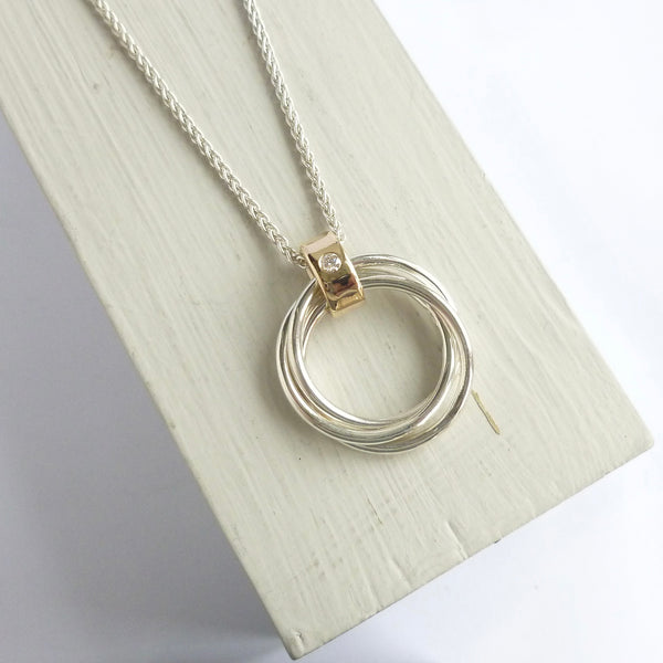 Silver necklace with a circular pendant on a light wooden surface