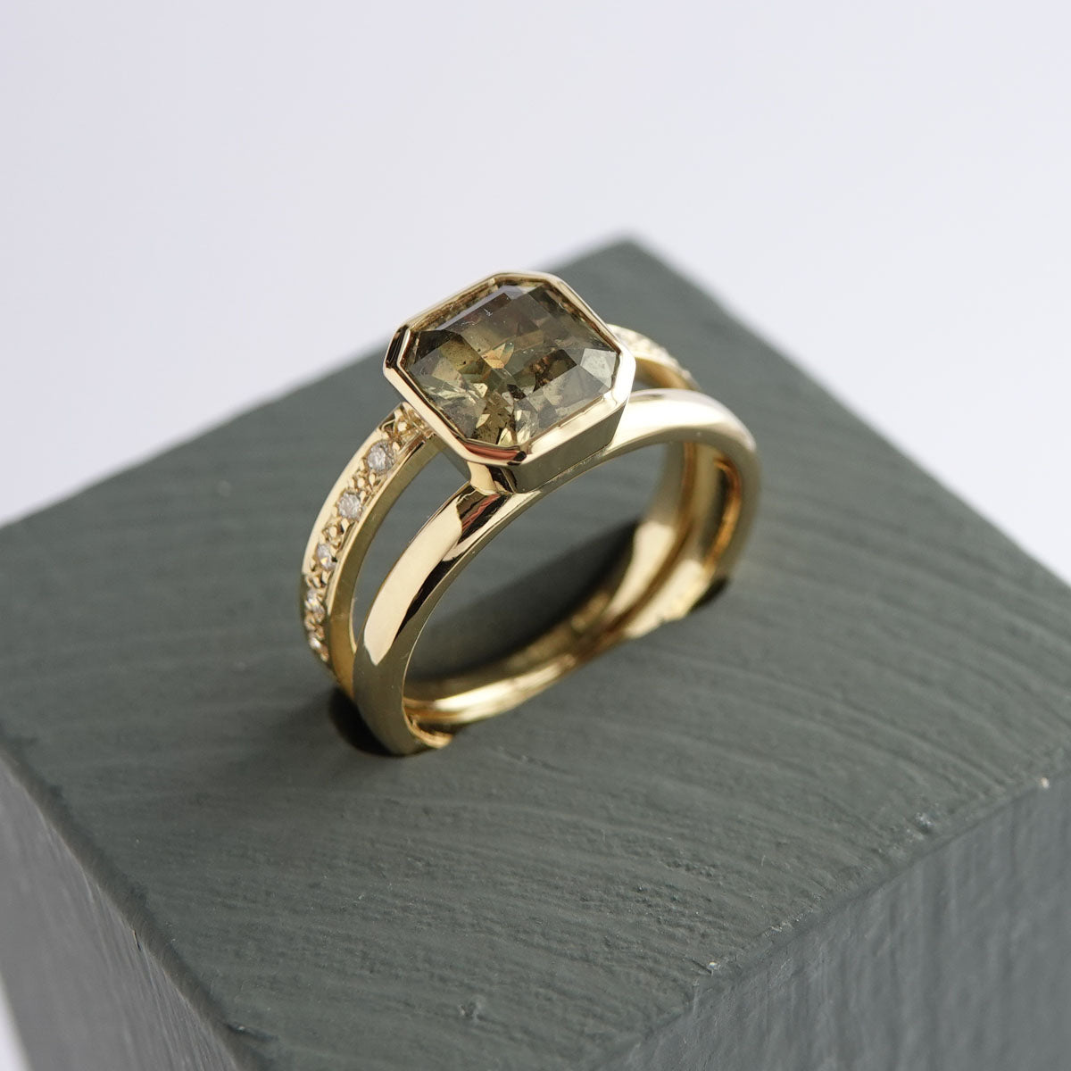 Close up of octagonal olive green sapphire and pavé diamond band in 18ct gold ring
