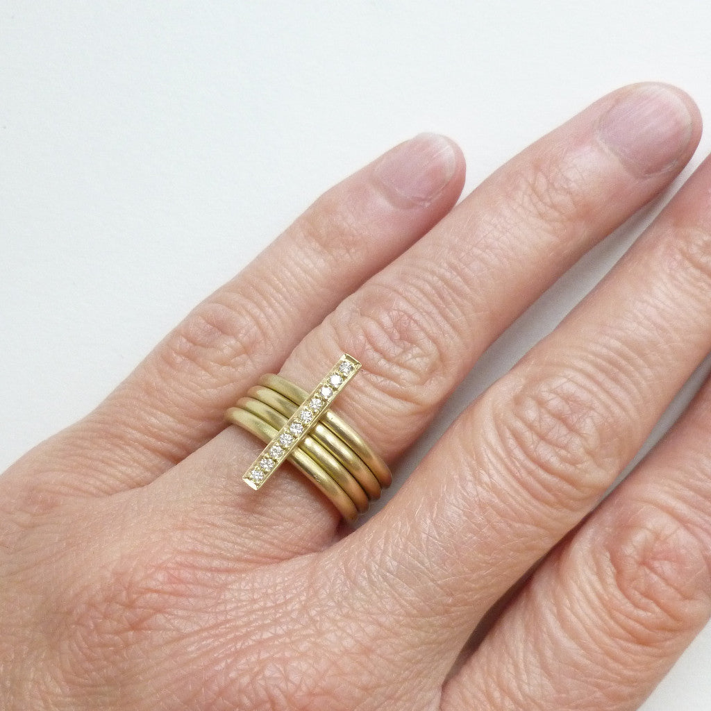 A heavy weight modern four band stacking gold ring with a row of pave diamonds. Multi band ring or interlocking ring.
