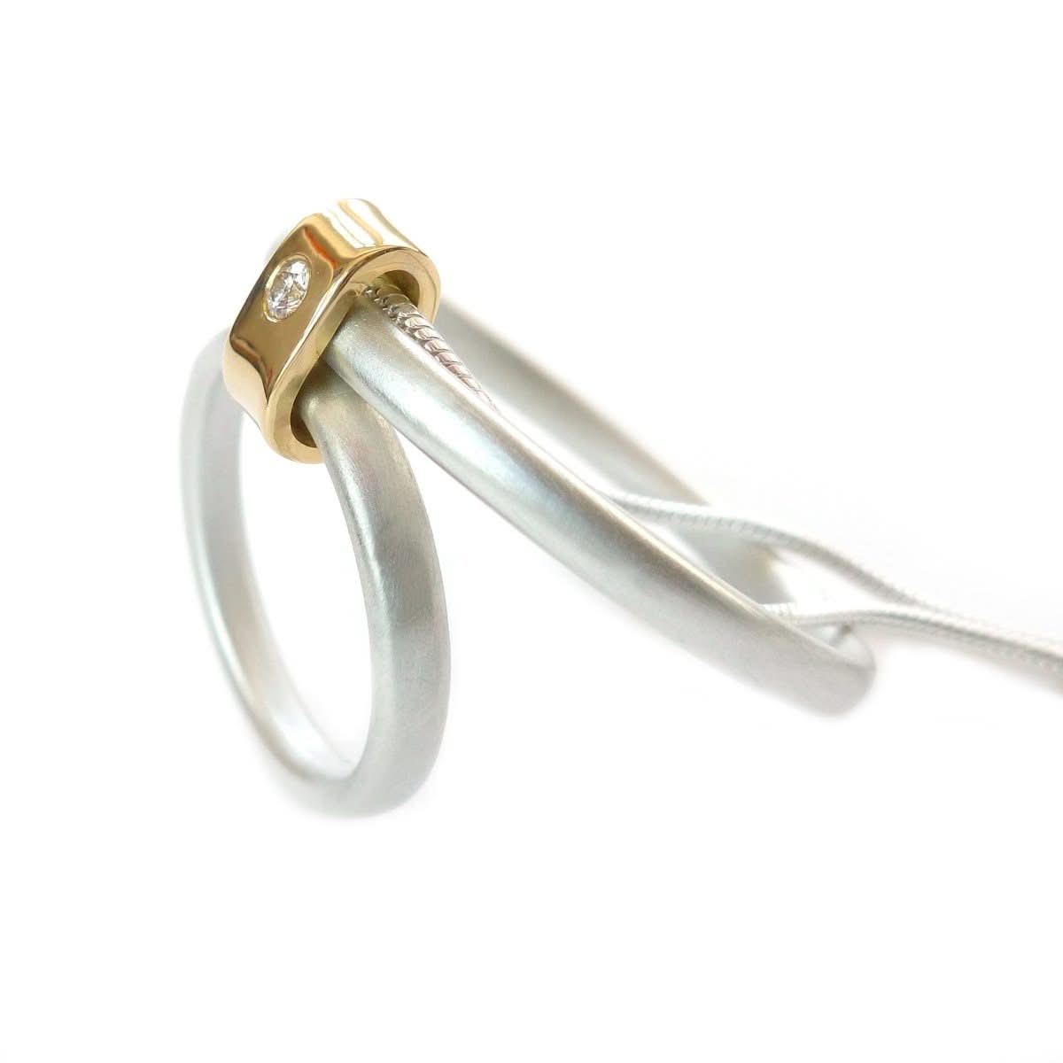 Detail of a 2.2mm diamond flush-set in a polished 18ct gold loop with a soft matt silver finish