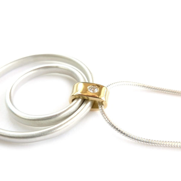 Side view of the contemporary pendant showing two freely moving silver rings on a fluid snake chain.