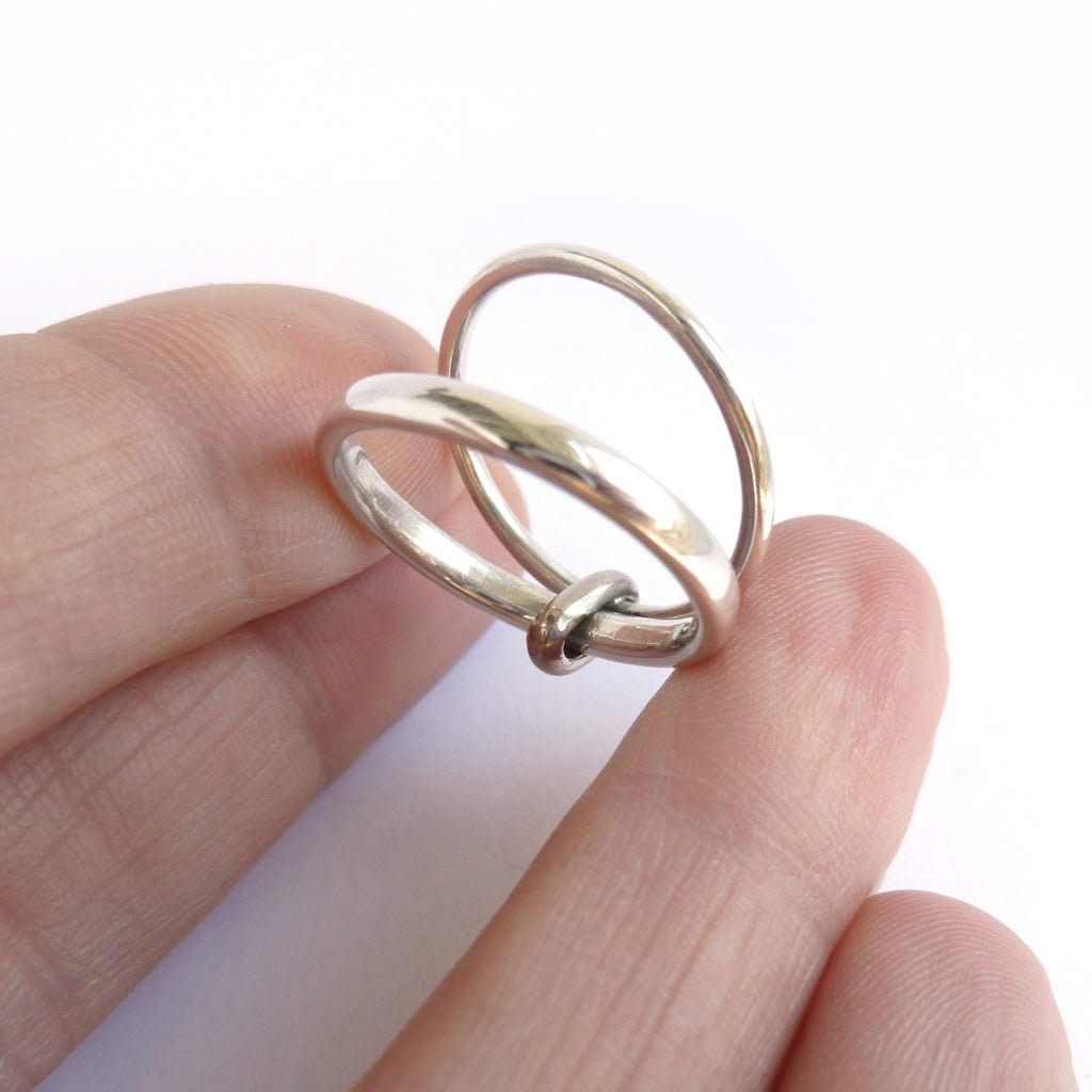 Contemporary silver double‑band ring with a polished 18ct gold loop showing gentle spinner‑style movement.