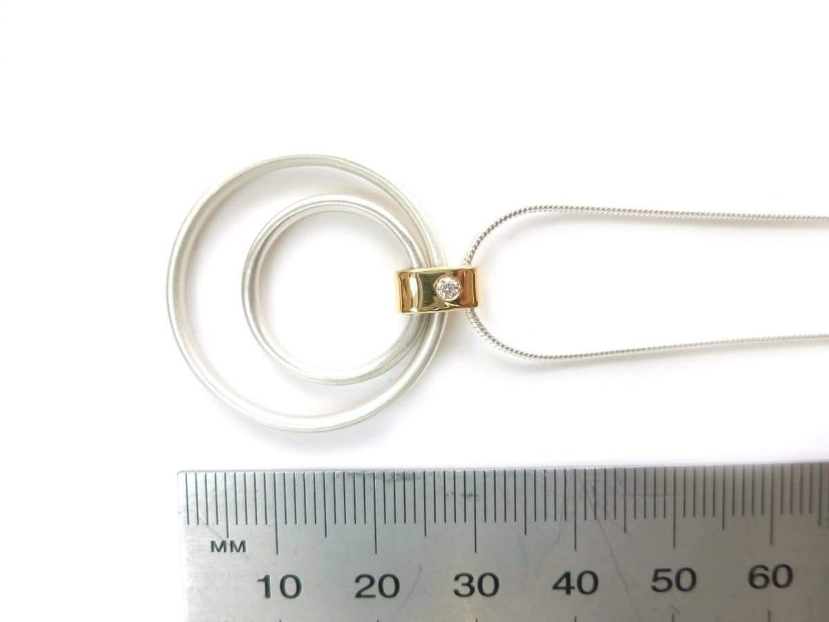Close-up of a 2.2mm diamond flush-set in a polished 18ct gold loop with a soft matt silver finish.