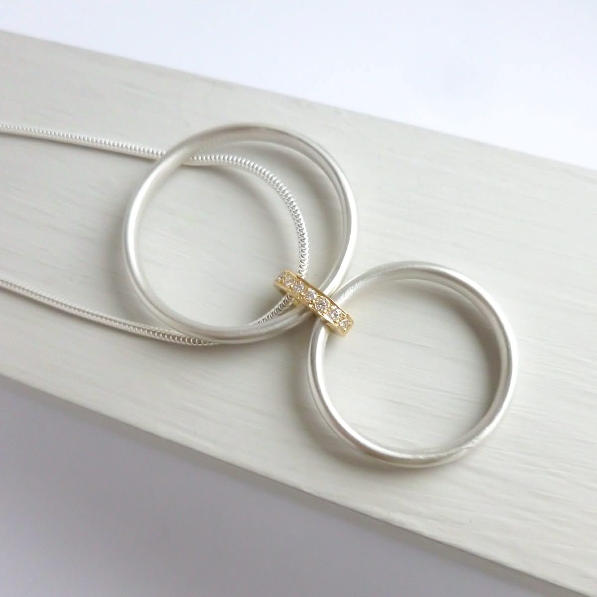 Detail of two interlocking silver circles that move freely on a contemporary diamond necklace.