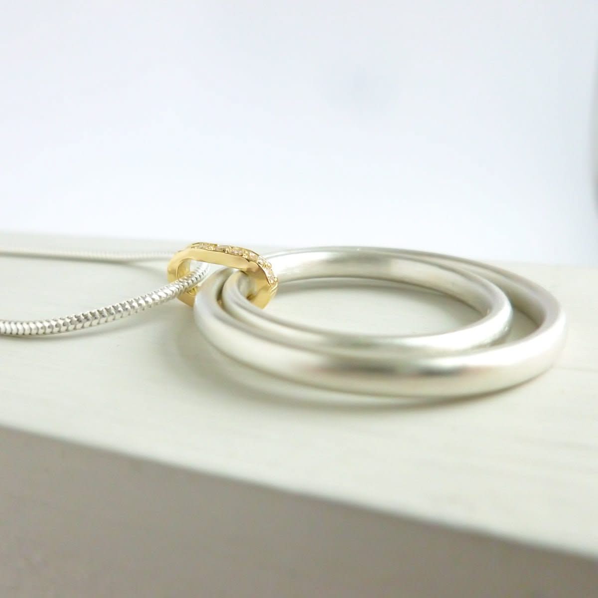 Side view of 7 white diamonds set into a polished gold loop and silver circles.