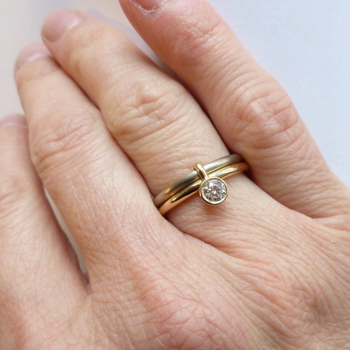 A unique modern contemporary 18ct gold two tone stacking engagement ring with white diamond. Multi band ring or interlocking ring, sometimes called double band ring too.